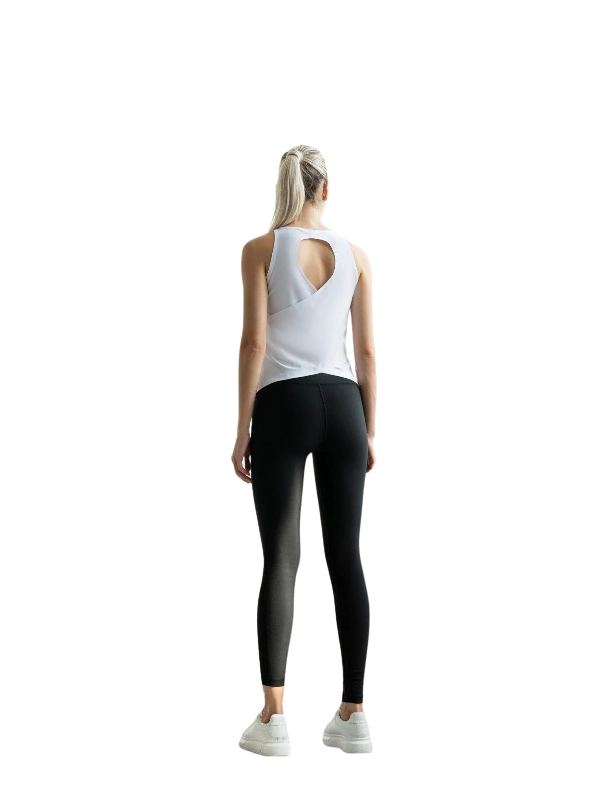 Eine Person trägt ein Lismina 089 Sport-Top in Weiss mit schwarzen Leggings, steht mit abgewandtem Blick auf einem weißen Hintergrund.